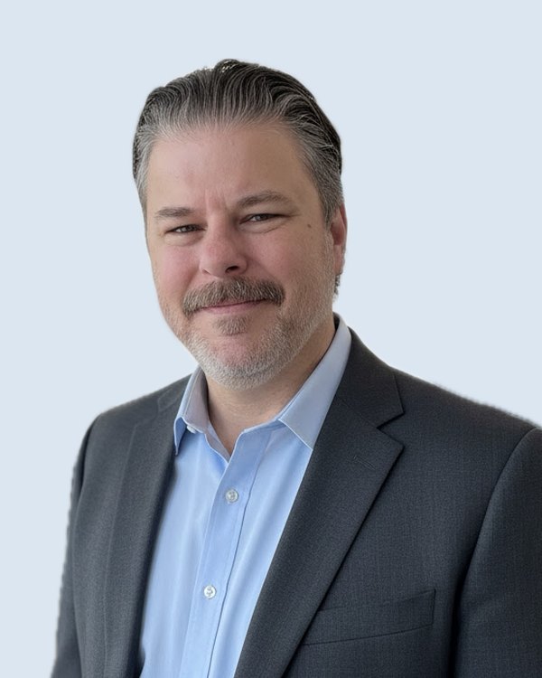 Skip, smiling, in a gray blazer and light blue shirt
